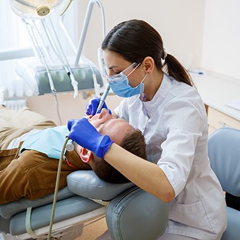 A female dentist treating a male patient’s dental emergency