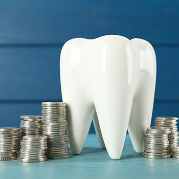 A large model tooth surrounded by stacks of coins