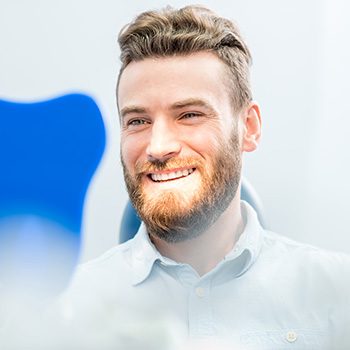 A handsome man looking at his smile in a hand mirror