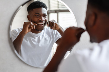 Man smiling while flossing his teeth