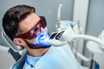 Man with dark hair having teeth whitened with UV light